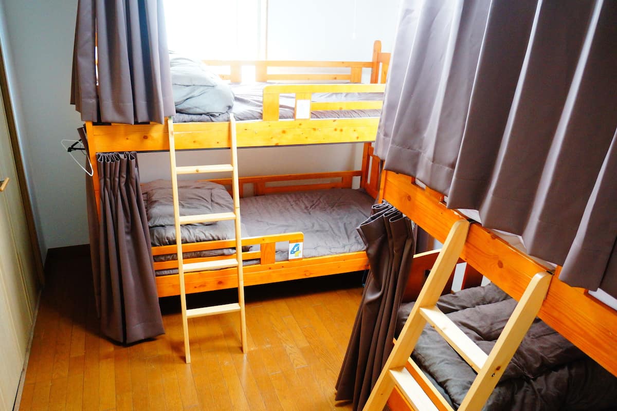 Una habitación con literas, suelo de madera y cortinas.