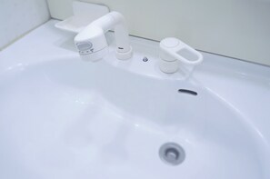 A white bathroom sink with a modern faucet and a soap dispenser. - Osaka Tomato Hostel (Osaka)