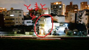 Un quartier résidentiel comprenant plusieurs immeubles, un parking et une petite maison, cette dernière étant mise en évidence par un cercle rouge.