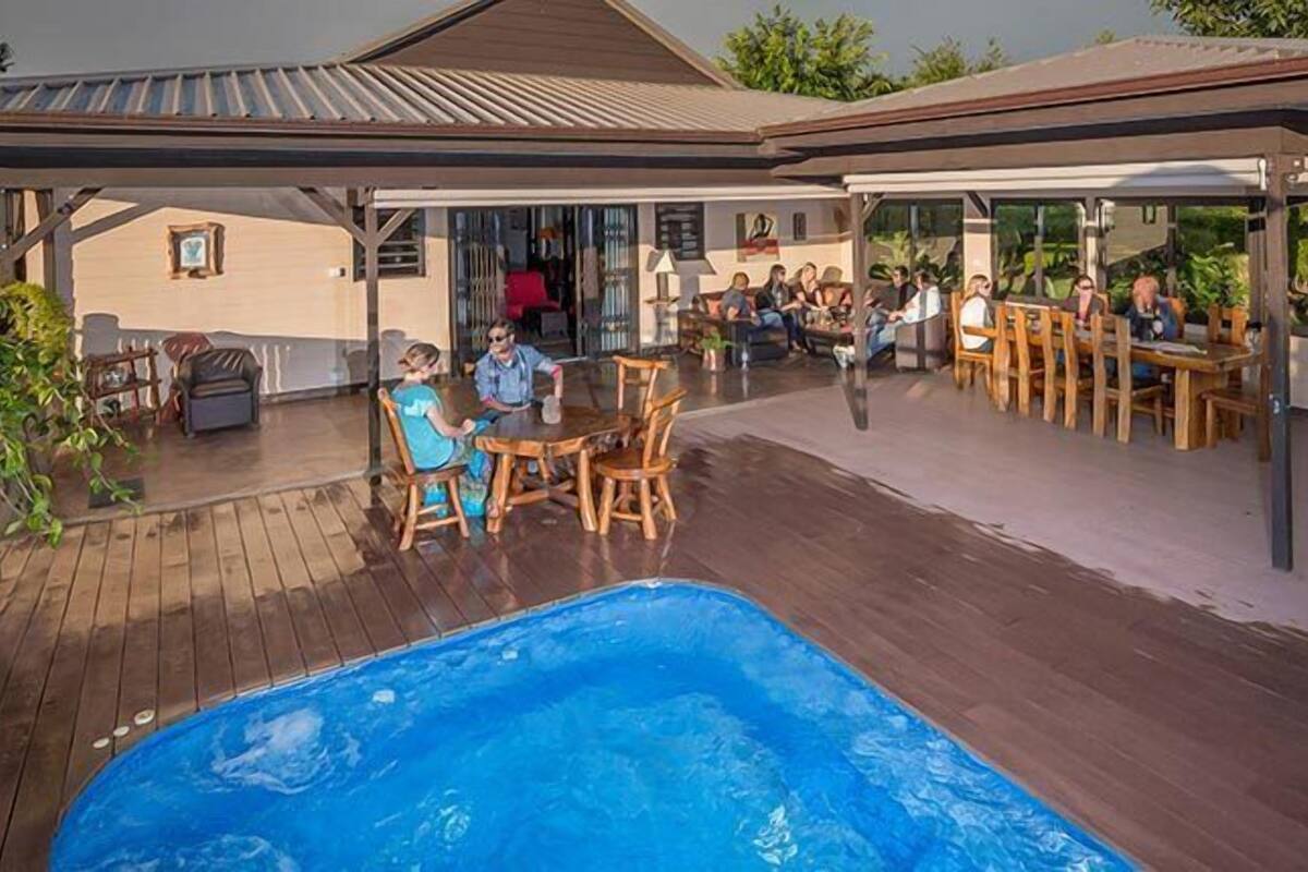 Un espace extérieur abrité comprenant une piscine, une terrasse en bois et des sièges.