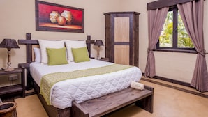 A neatly made bed with a green throw, a wooden bench, and a painting above it. - 7 Cascades Restaurant Bar & Lodges (Vacoas-Phoenix)