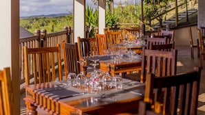 A restaurant with wooden tables and chairs, set for dining with wine glasses and cutlery. - 7 Cascades Restaurant Bar & Lodges (Vacoas-Phoenix)