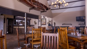 A restaurant with wooden tables and chairs, a bar area, and a chandelier. - 7 Cascades Restaurant Bar & Lodges (Vacoas-Phoenix)