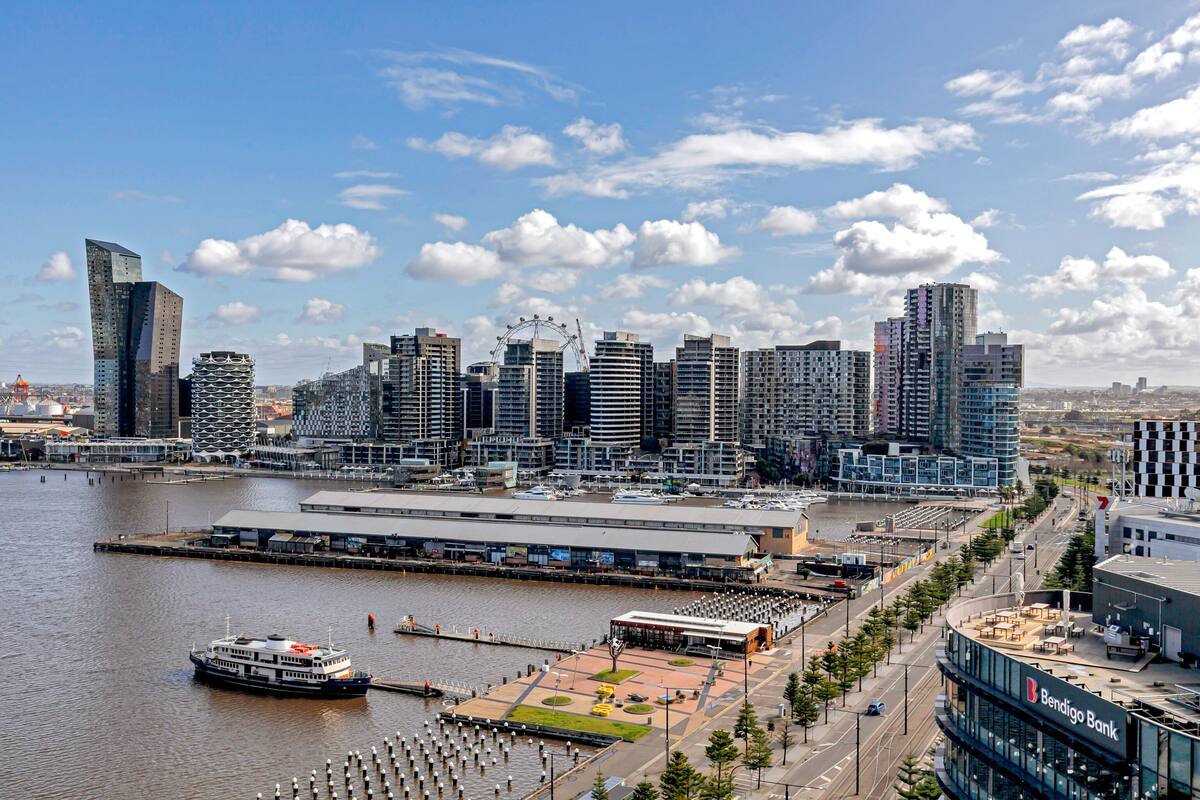 A waterfront cityscape with modern buildings, a river, and a Ferris wheel.