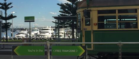 A tram station with a green tram and directional signs.