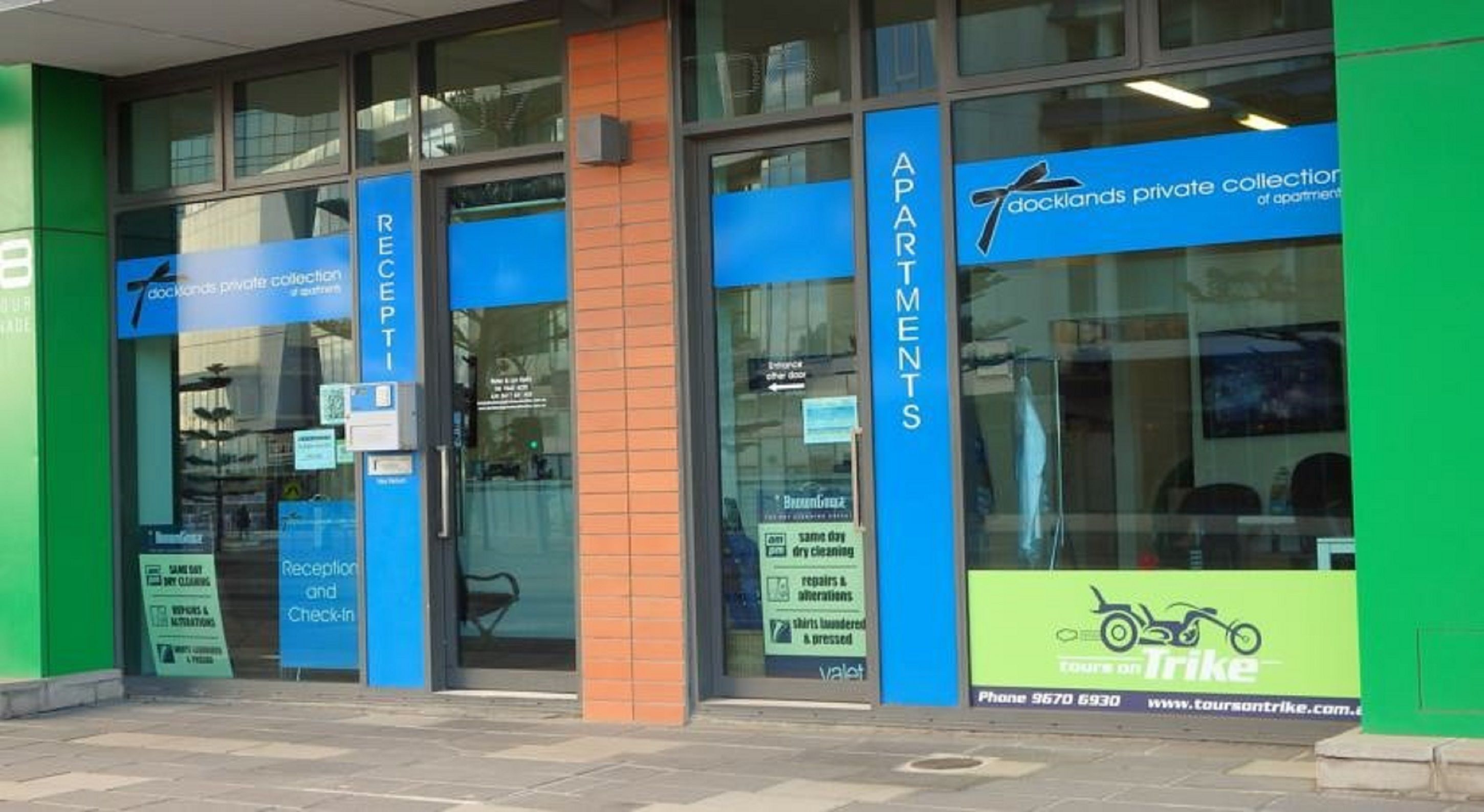 A building with blue signage for 'Reception and Check-In' and 'Apartments'.