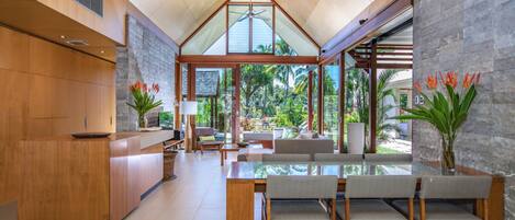 A modern kitchen with wooden cabinetry, a glass dining table, and a view of the outdoors.