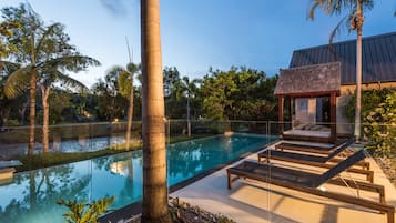 Una piscina al aire libre, sombrillas, sillones reclinables de piscina