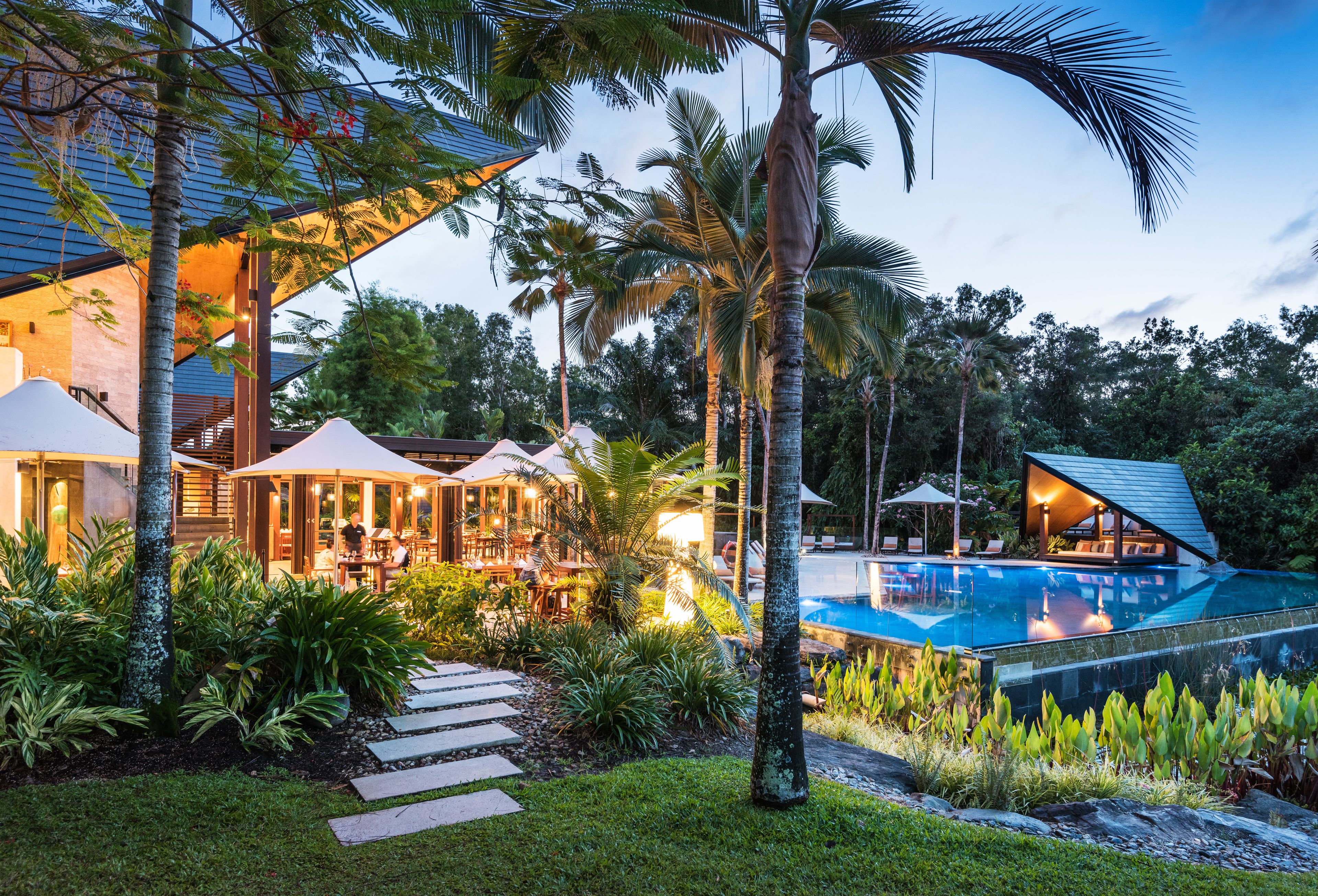 A resort with a swimming pool, outdoor seating, and lush greenery.