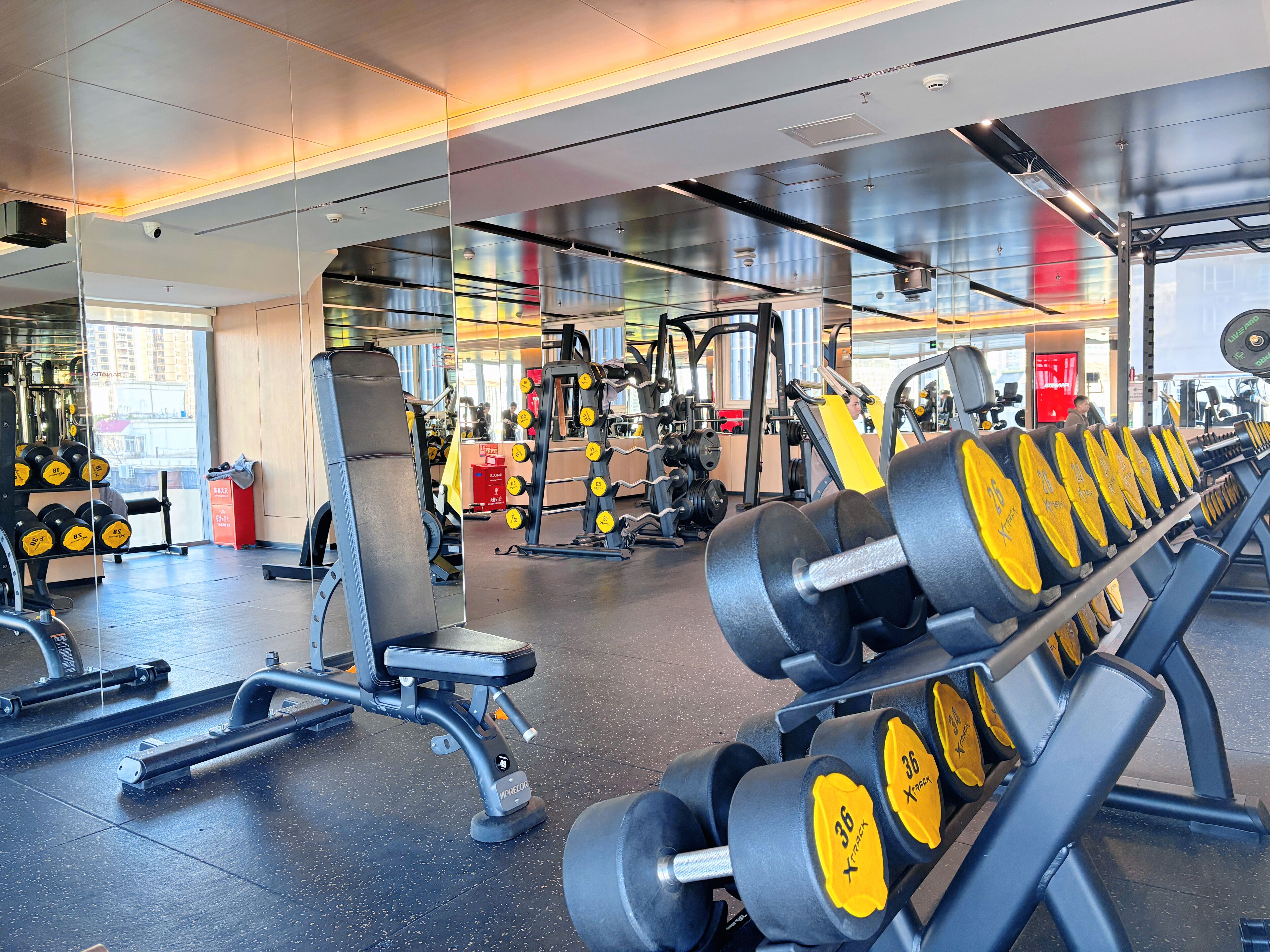 Un gimnasio con equipo de levantamiento de pesas, bancos y diversas máquinas.