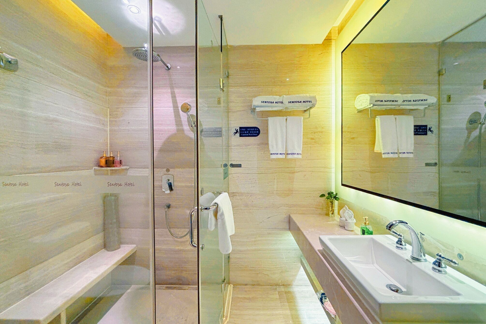 A modern bathroom with a glass shower enclosure, a large mirror, and a dual sink setup.