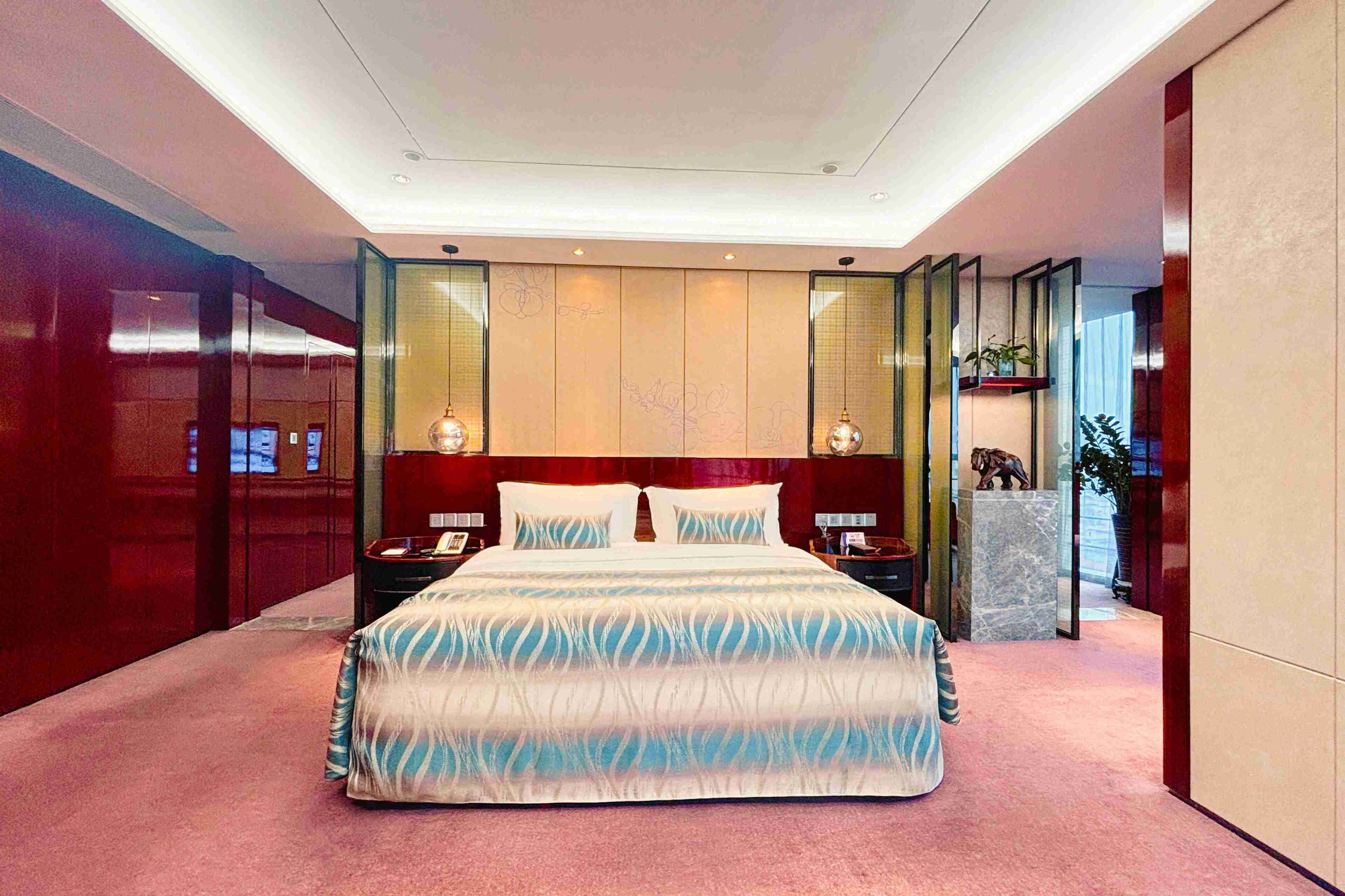 A modern bedroom with a large bed, a nightstand, a lamp, and a decorative shelf.