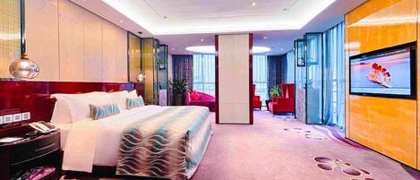 Una habitación de hotel moderna con una cama grande, un escritorio con computadora y un televisor en la pared.