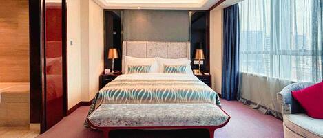 A modern hotel room with a large bed, bedside lamps, a sofa, and a view of the city through the window.