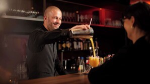 Un cantinero sirviendo una bebida en un vaso en la barra.