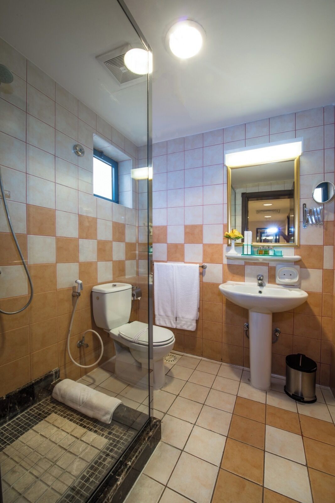 Un baño con cabina de ducha de vidrio, inodoro, lavamanos y espejo.