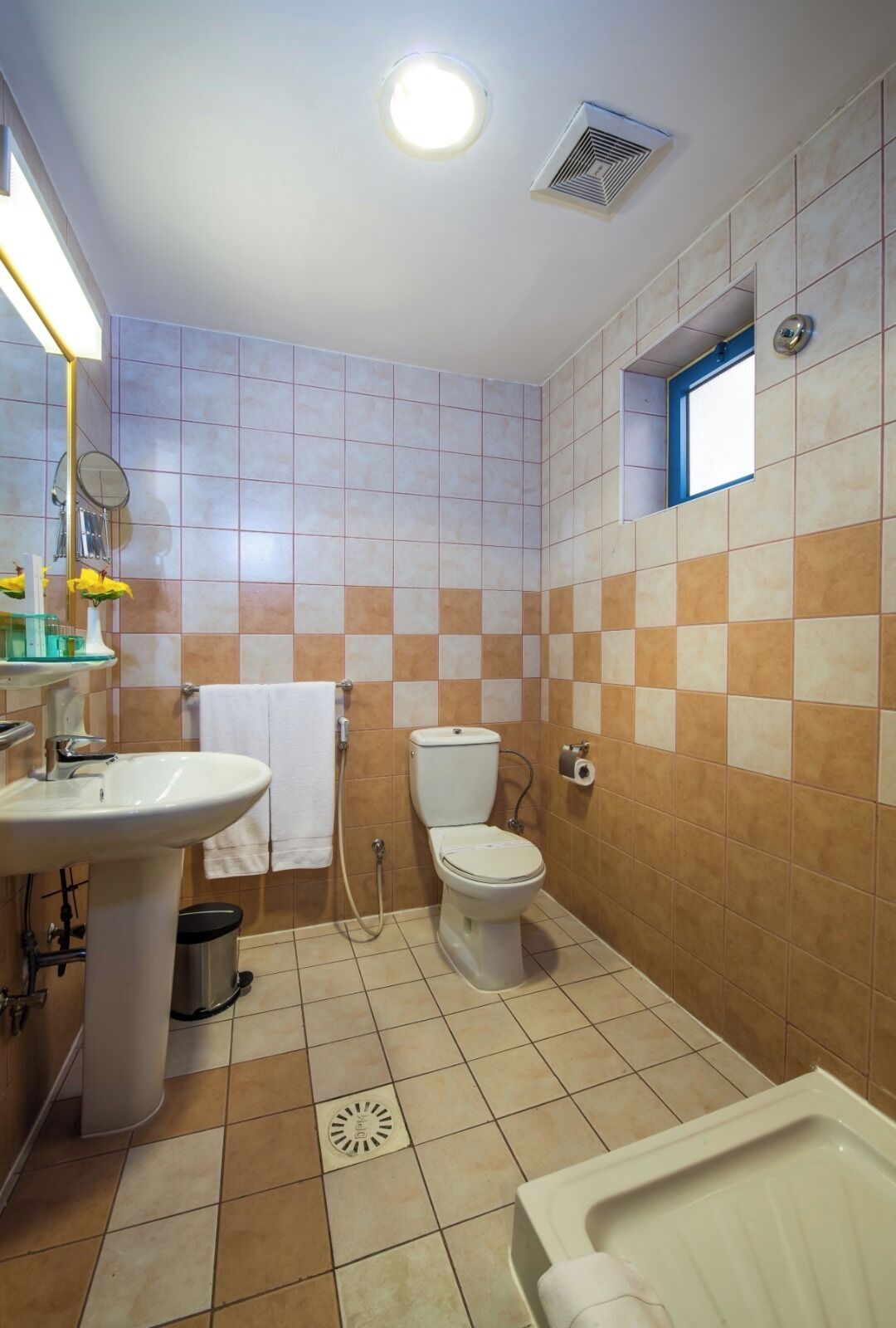 A bathroom with a sink, toilet, and bathtub, tiled in beige and brown.