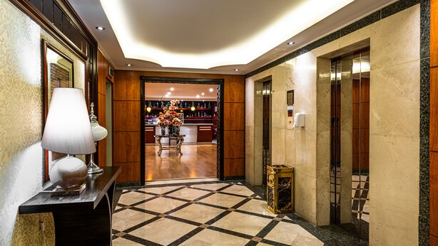 A hotel lobby with a checkered floor, a reception desk, and a bar area visible through an open door. - Boudl Abha (Abha)