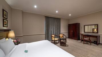 Una habitación de hotel con una cama grande, dos sillas, un escritorio, una lámpara y un espejo.