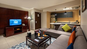 A modern living room with a television, sofa, coffee table, and a kitchen area with a microwave and sink. - Boudl Abha (Abha)