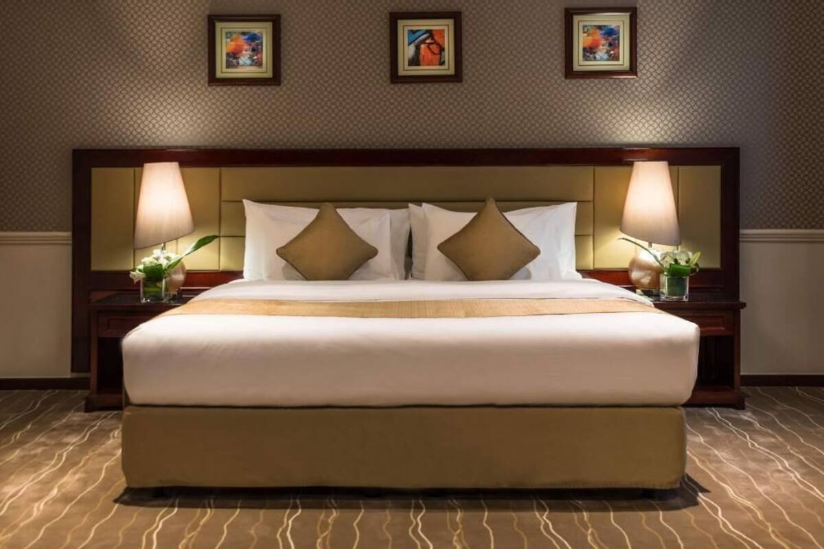 A hotel room with a large bed, two bedside tables with lamps, and three framed pictures on the wall.
