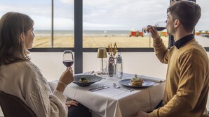 Una mesa de comedor con vista al mar, una vela y una botella de agua.