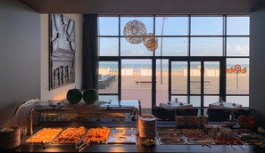 A buffet area with a view of the beach through large windows.