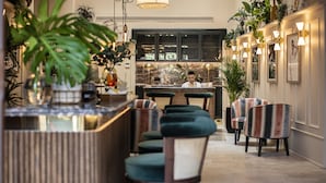 Un espace bar comprenant un comptoir, des tabourets de bar et un coin salon avec des chaises.