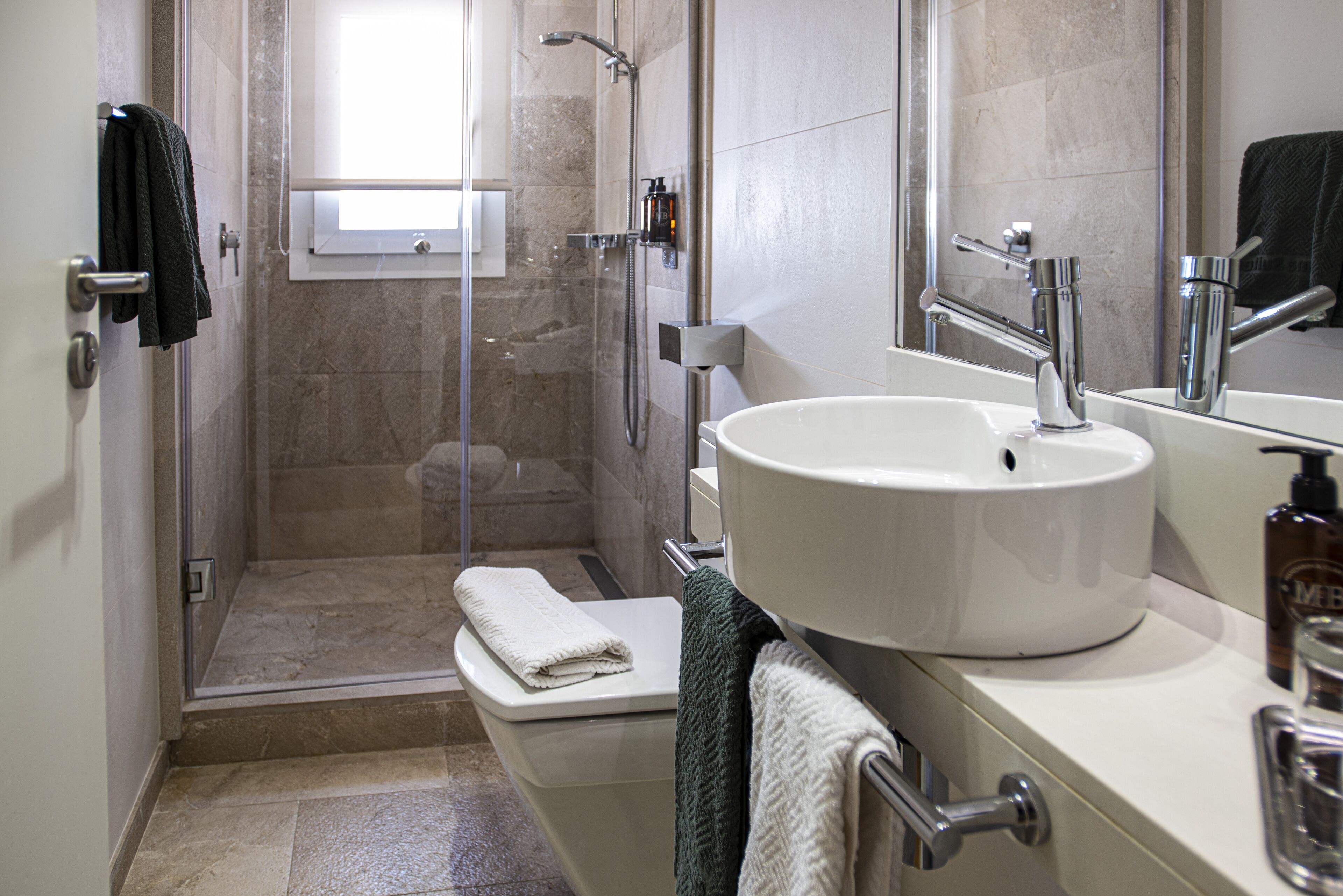 Ein Badezimmer mit Dusche, Toilette, Waschbecken und Spiegel.