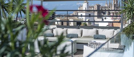 Terraza en la azotea con zona de estar, vista panorámica de la ciudad y cielo despejado.