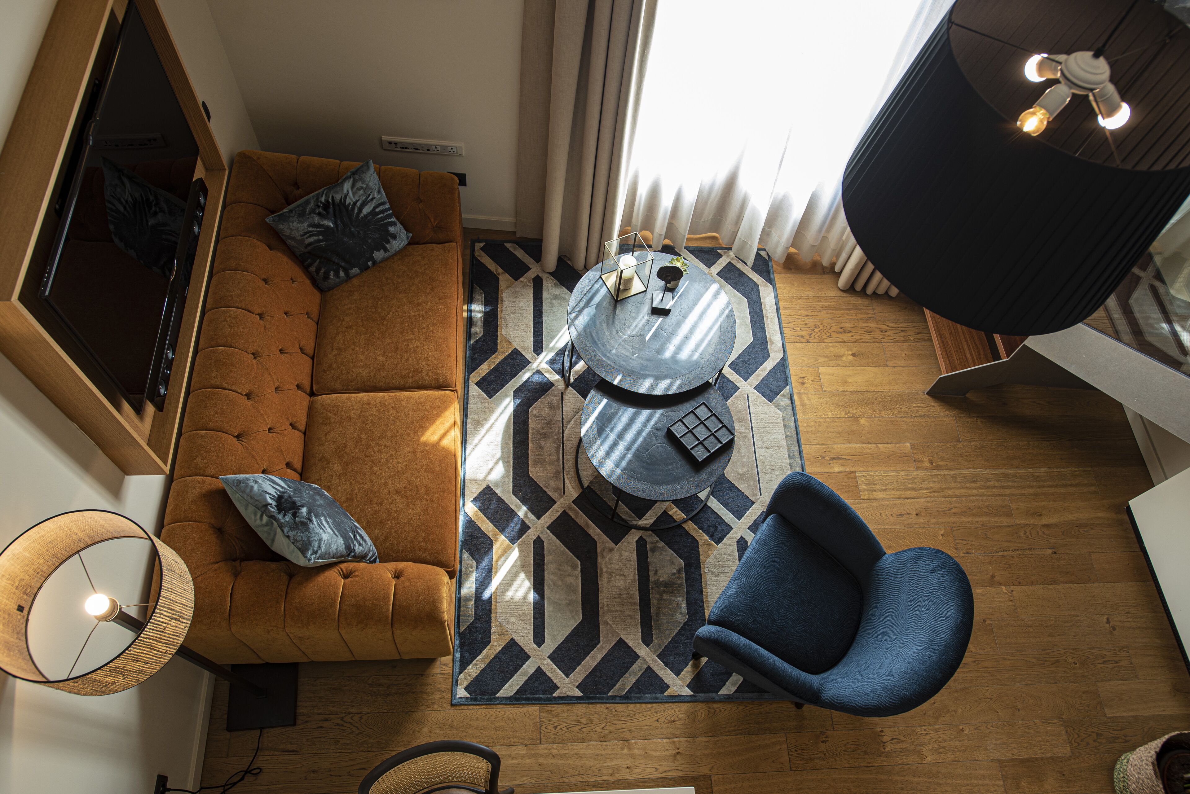 A modern living room with a brown sofa, a blue armchair, a round coffee table, and a patterned rug.