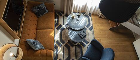 A modern living room with a brown sofa, a blue armchair, a round coffee table, and a patterned rug.
