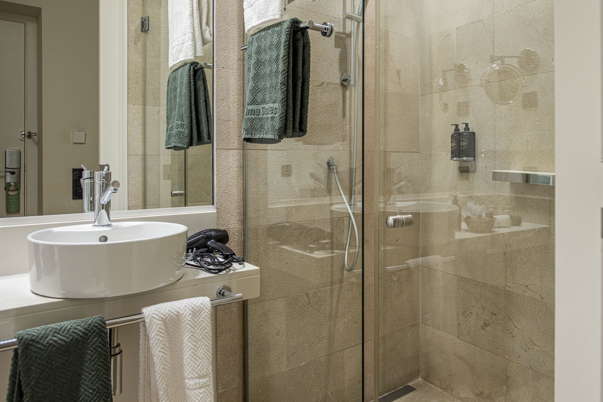 A modern bathroom with a glass-enclosed shower, a white sink, and a mirror.