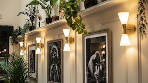 Un couloir agrémenté d’œuvres d’art encadrées, d’appliques murales et de plantes en pot.