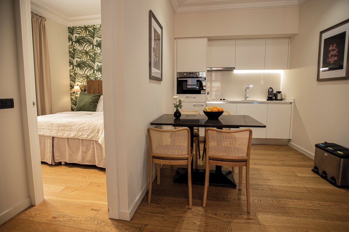 Un espacio habitable pequeño con cama, kitchenette y zona de comedor.