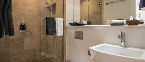 A modern bathroom with a glass-enclosed shower, a white sink, and a mirror above the sink.