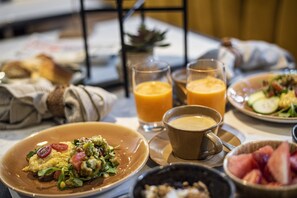 A breakfast setting with plates of food, glasses of orange juice, and a cup of coffee.