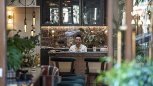 Un espace bar doté d’un comptoir en marbre, de tabourets de bar et de luminaires suspendus.