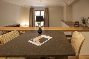 A dining area with a dark marble table, wicker chairs, a vase with flowers, and a magazine titled "IN PALMA".