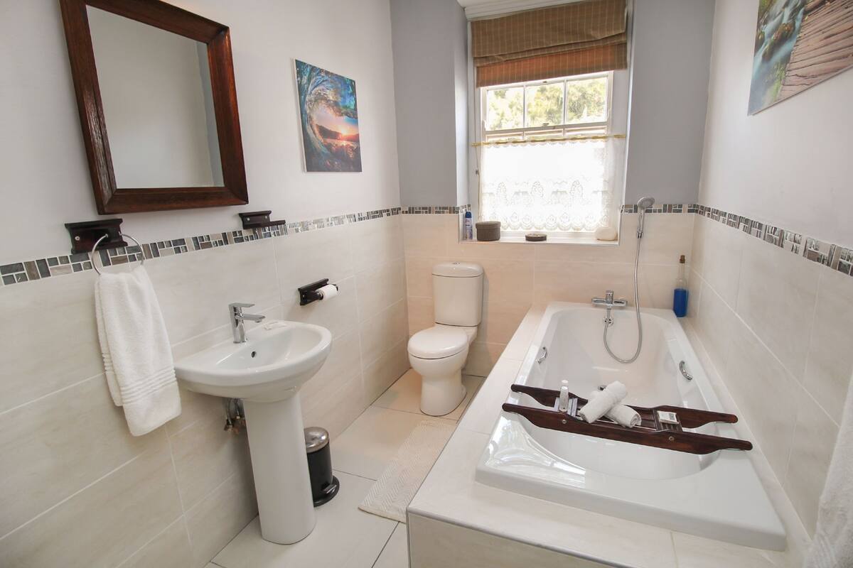 A modern bathroom with a sink, toilet, and bathtub.