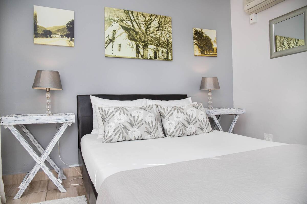 A bedroom with a bed, two bedside tables, and three wall-mounted pictures.
