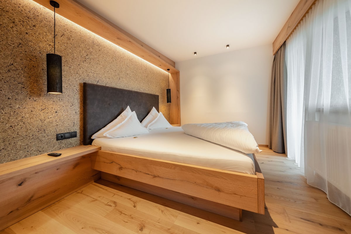 A modern bedroom with a wooden bed, a headboard, and a wall-mounted light fixture.