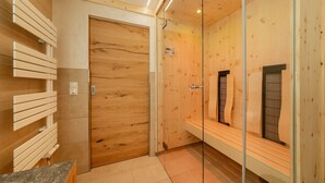 Un baño moderno con paneles de madera, cabina de ducha de vidrio y un banco.