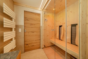 Un baño moderno con paneles de madera, cabina de ducha de vidrio y un banco.