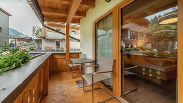 Una cucina moderna con travi in legno, un angolo bar con posti a sedere e un'ampia finestra che si affaccia su un giardino.