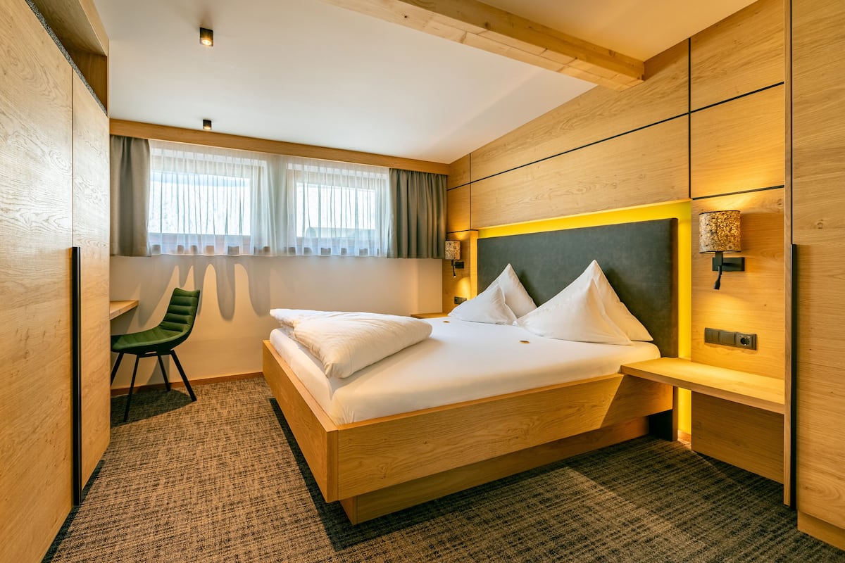 A modern hotel room with a wooden bed, a desk, and a chair.
