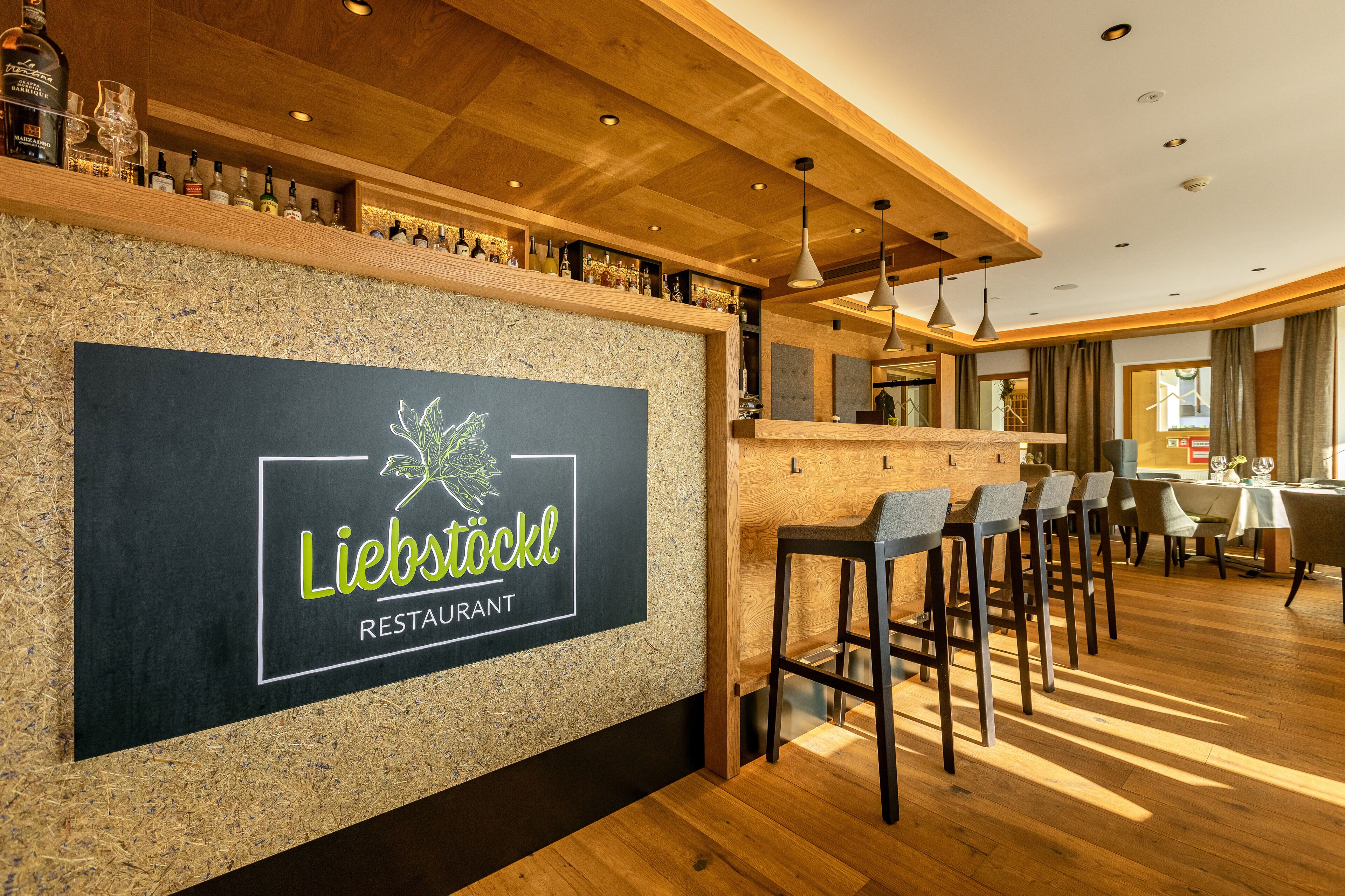 A restaurant interior with a wooden bar, seating area, and a sign reading "Liebstöckl Restaurant".