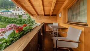 Un balcón de madera con mesa y sillas, con vista a un río y edificios.
