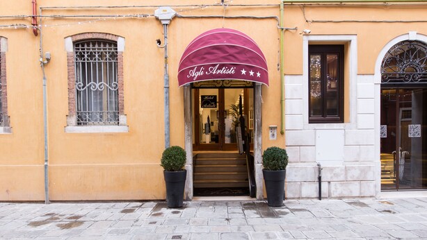 A building with a maroon awning labeled "Aglio Artistici" and a door with a sign "Hotel Artistici." - Hotel Agli Artisti (Venice)