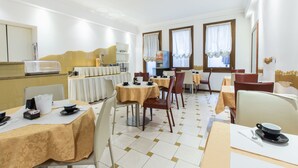 A hotel dining area with multiple tables and chairs, a buffet setup, and a view of the room. - Hotel Agli Artisti (Venice)